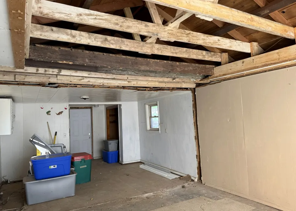 Exposed ceiling framing and the remaining interior walls.